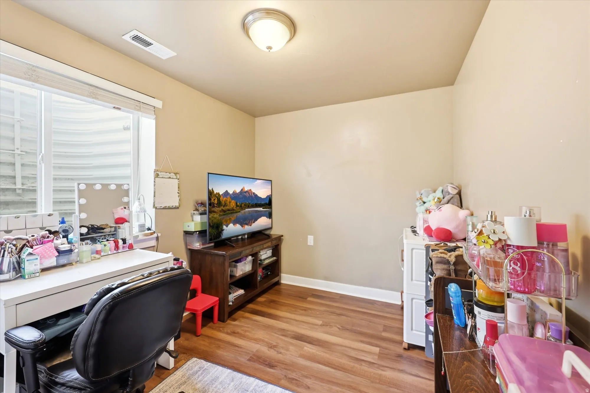 Recessed window with a window well, wood-finish flooring, neutral wall paint, white baseboards, and a flush mount ceiling light fixture