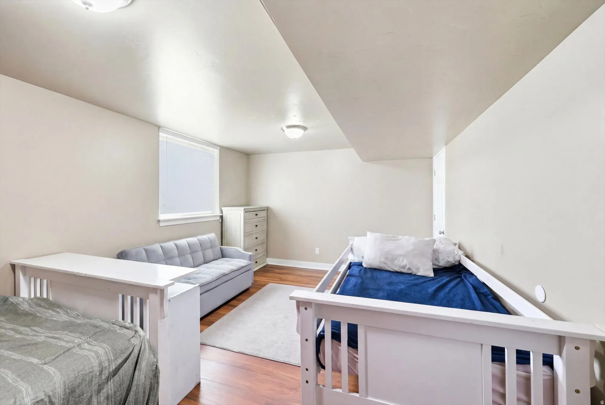 Spacious room featuring wood-finish flooring, light neutral wall tones, and recessed lighting