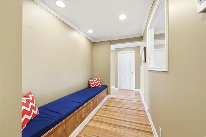 Hallway featuring an extended built-in bench, wood-finish flooring, recessed lighting, crown molding, and a paneled interior door