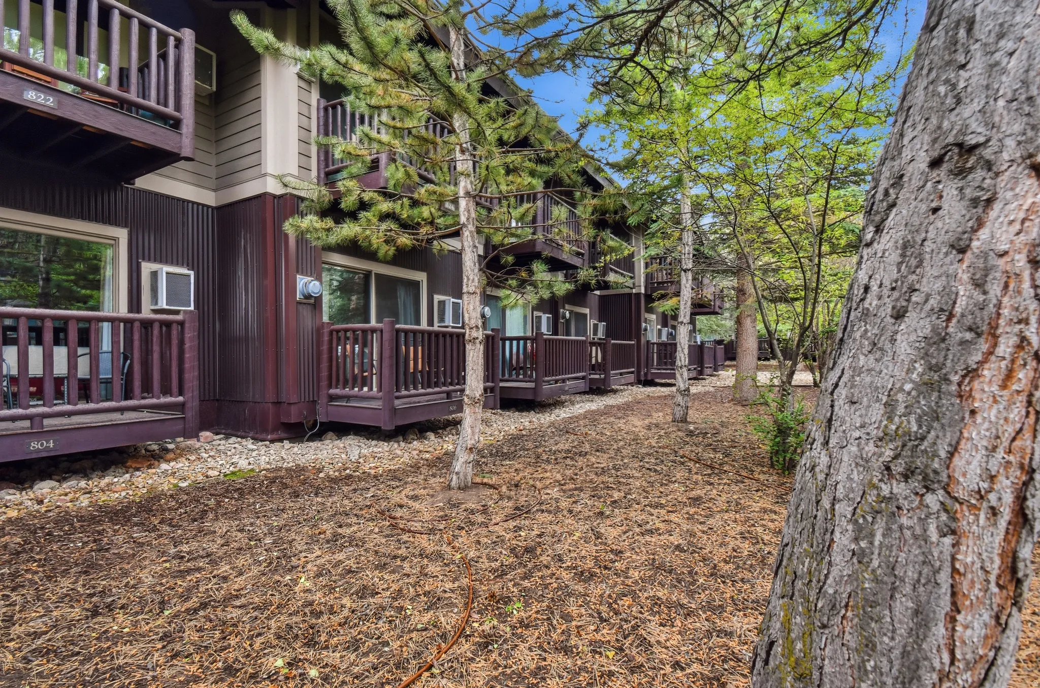 Ground-level patios and upper-level balconies featuring dark wood railings