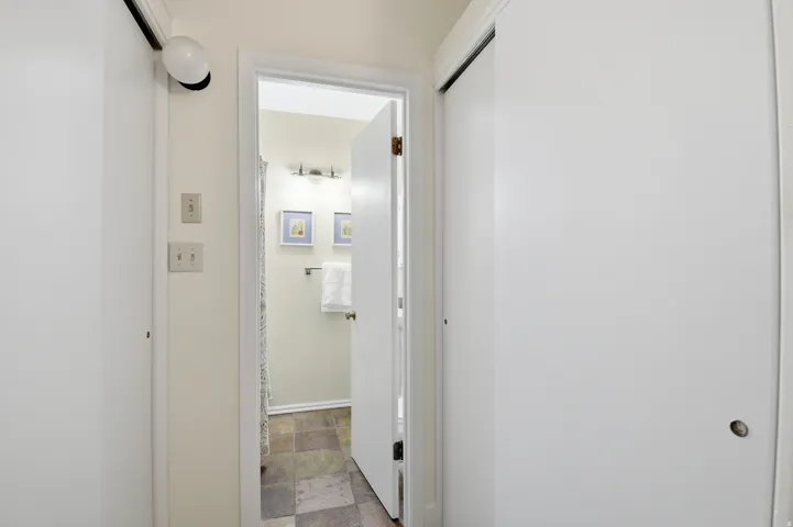 Hallway entrance featuring two white sliding closet doors, wall-mounted light fixture, and light switches
