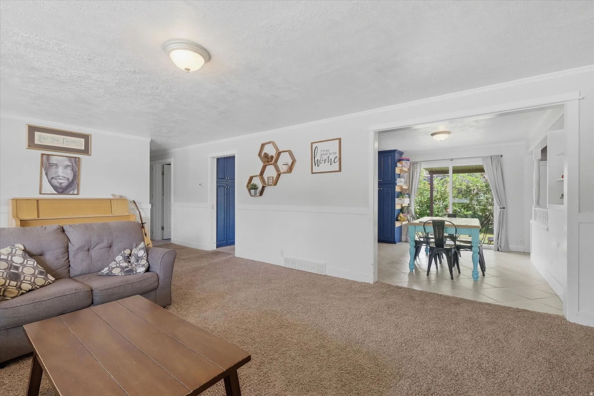 Spacious living area featuring neutral carpeting and white wainscoting