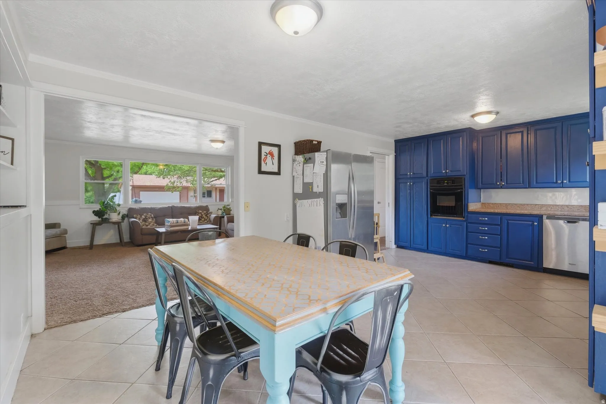 Spacious kitchen featuring blue cabinetry with brushed nickel hardware, light-toned countertops, and integrated stainless steel appliances
