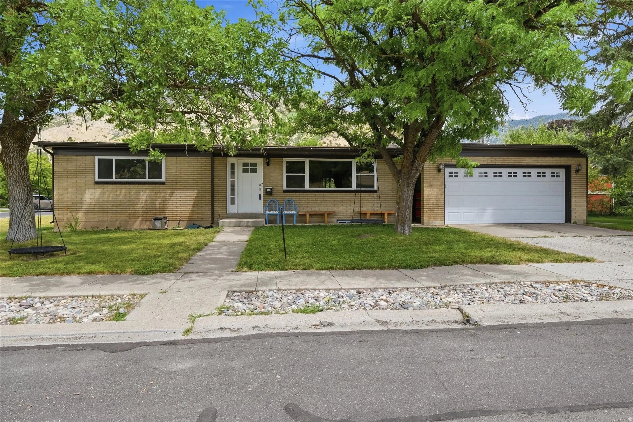Brick exterior featuring a two-car garage with paneling and window inserts