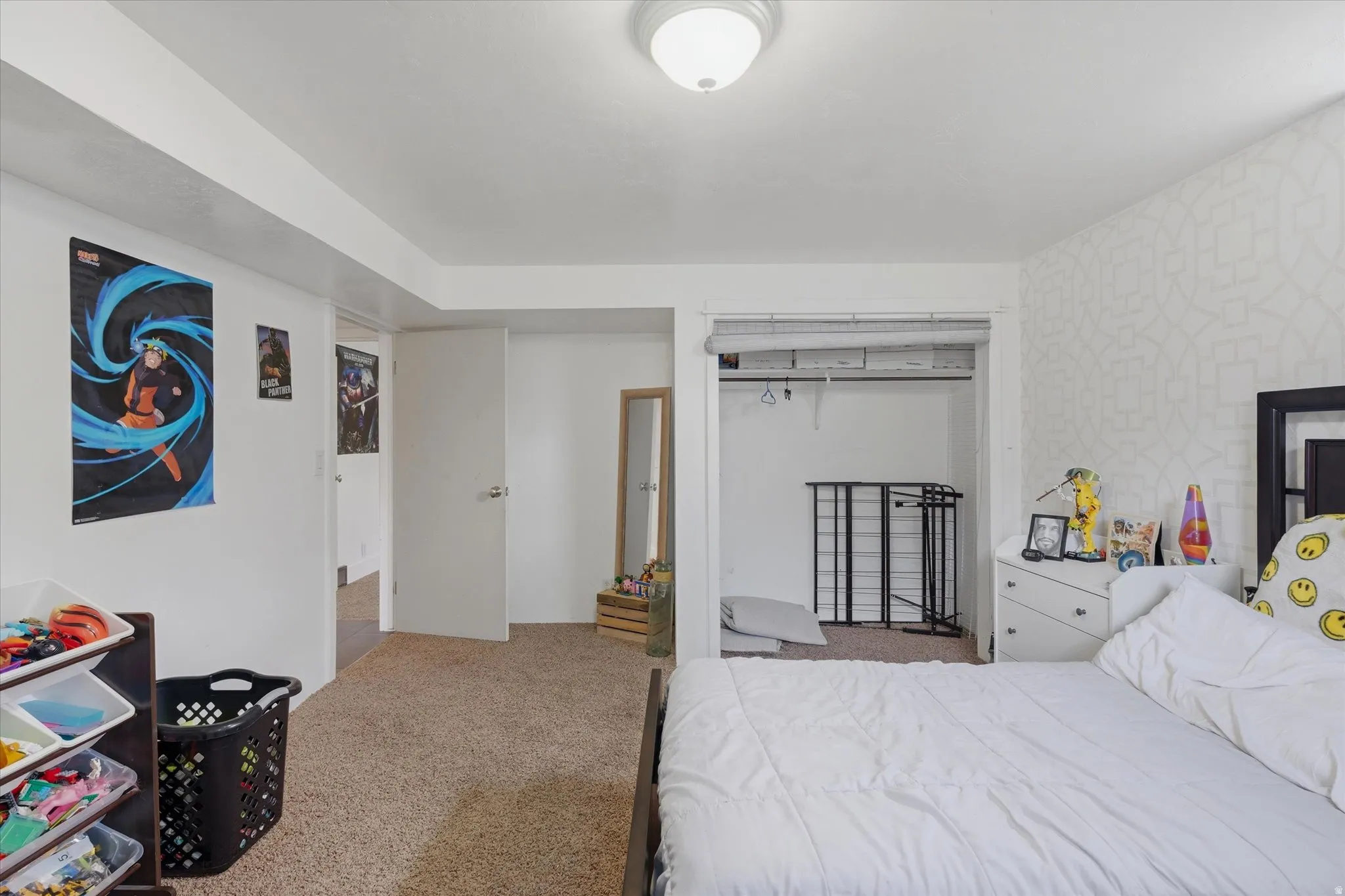 Carpeted room with white walls, a flush-mount ceiling light, and a patterned accent wall