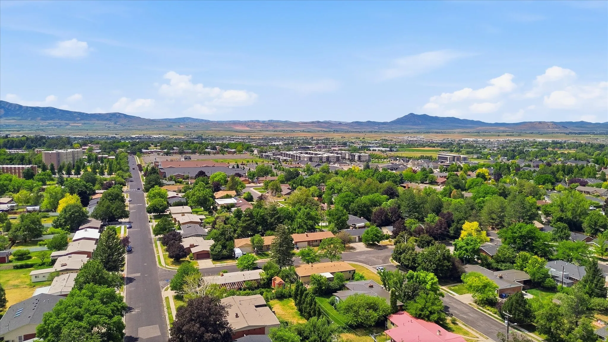 Suburban neighborhood with mature trees, residential streets, and distant mountain ranges
