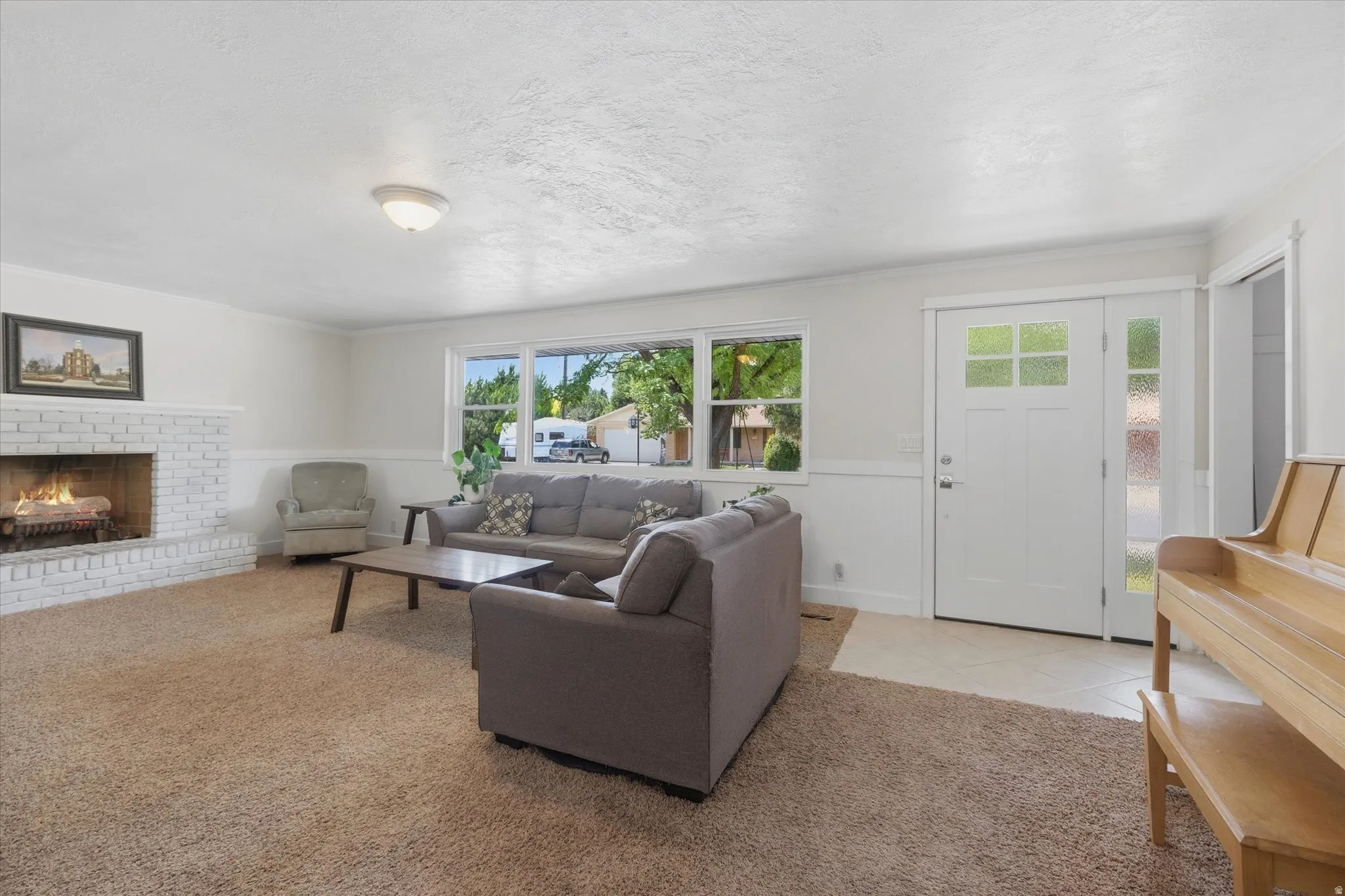 Bright living area featuring a white brick fireplace, expansive window, and neutral wall tones