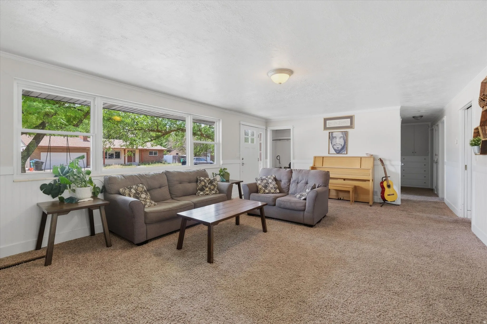 Spacious living area featuring light-toned carpet flooring and white painted walls