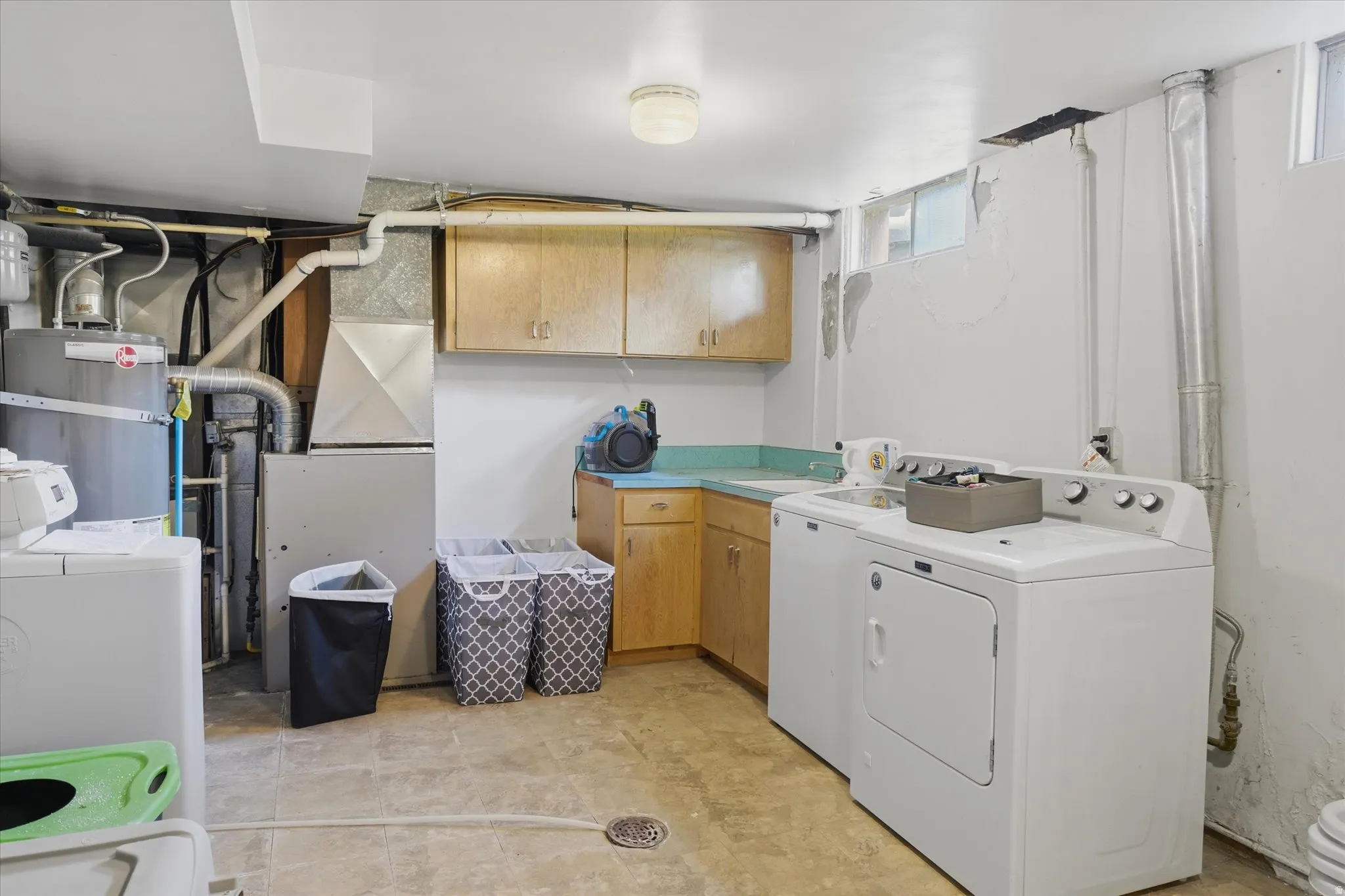 Laundry area featuring wood-finish cabinetry, a built-in sink with countertop, and utility hookups