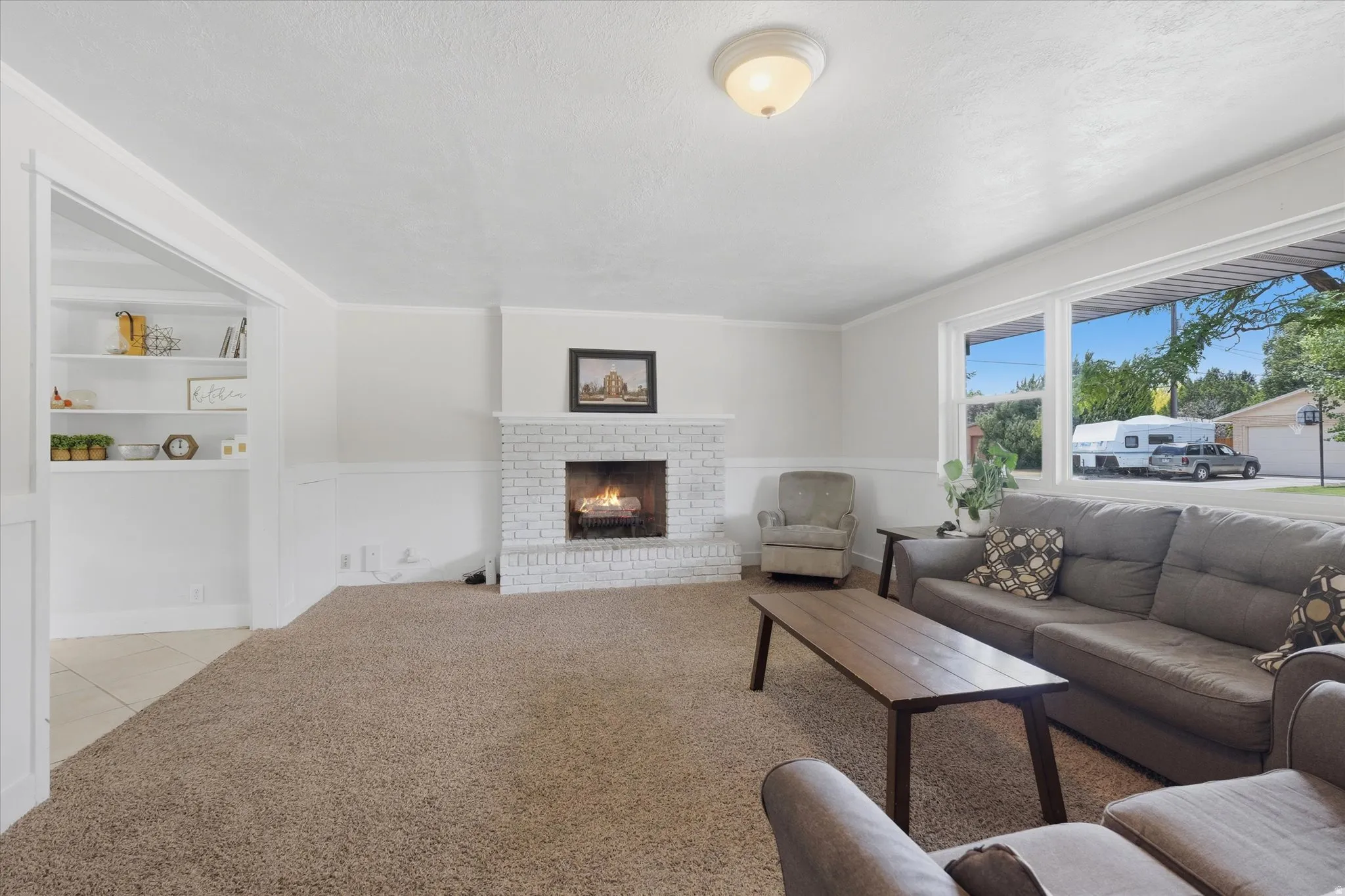 Living area featuring a white brick fireplace, built-in shelving, and carpet flooring