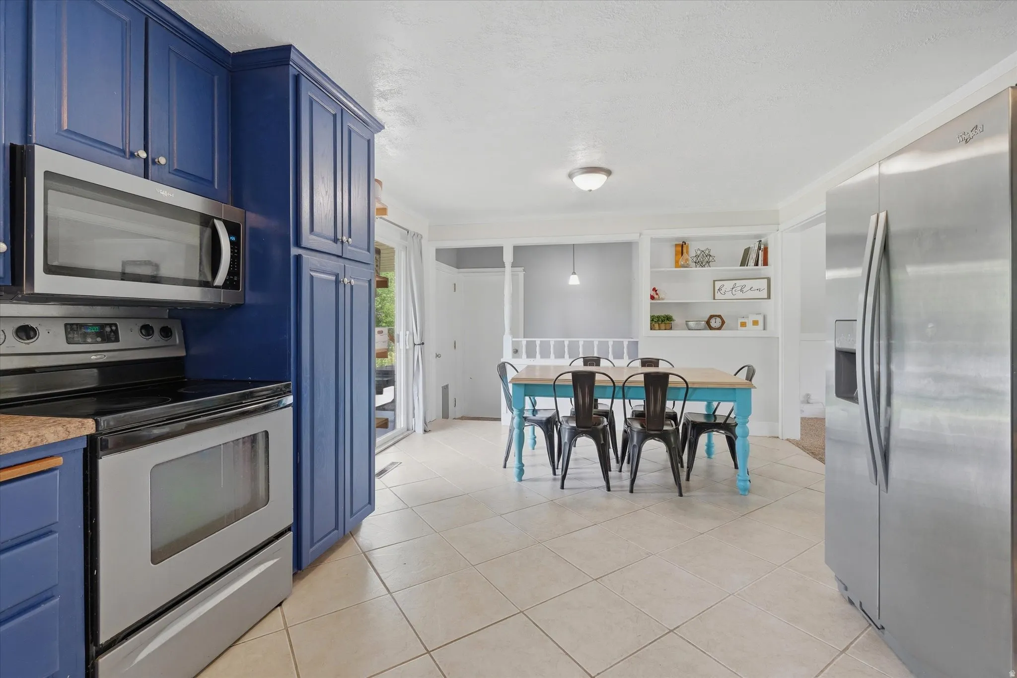 Kitchen featuring blue cabinetry, stainless steel appliances, and tile flooring