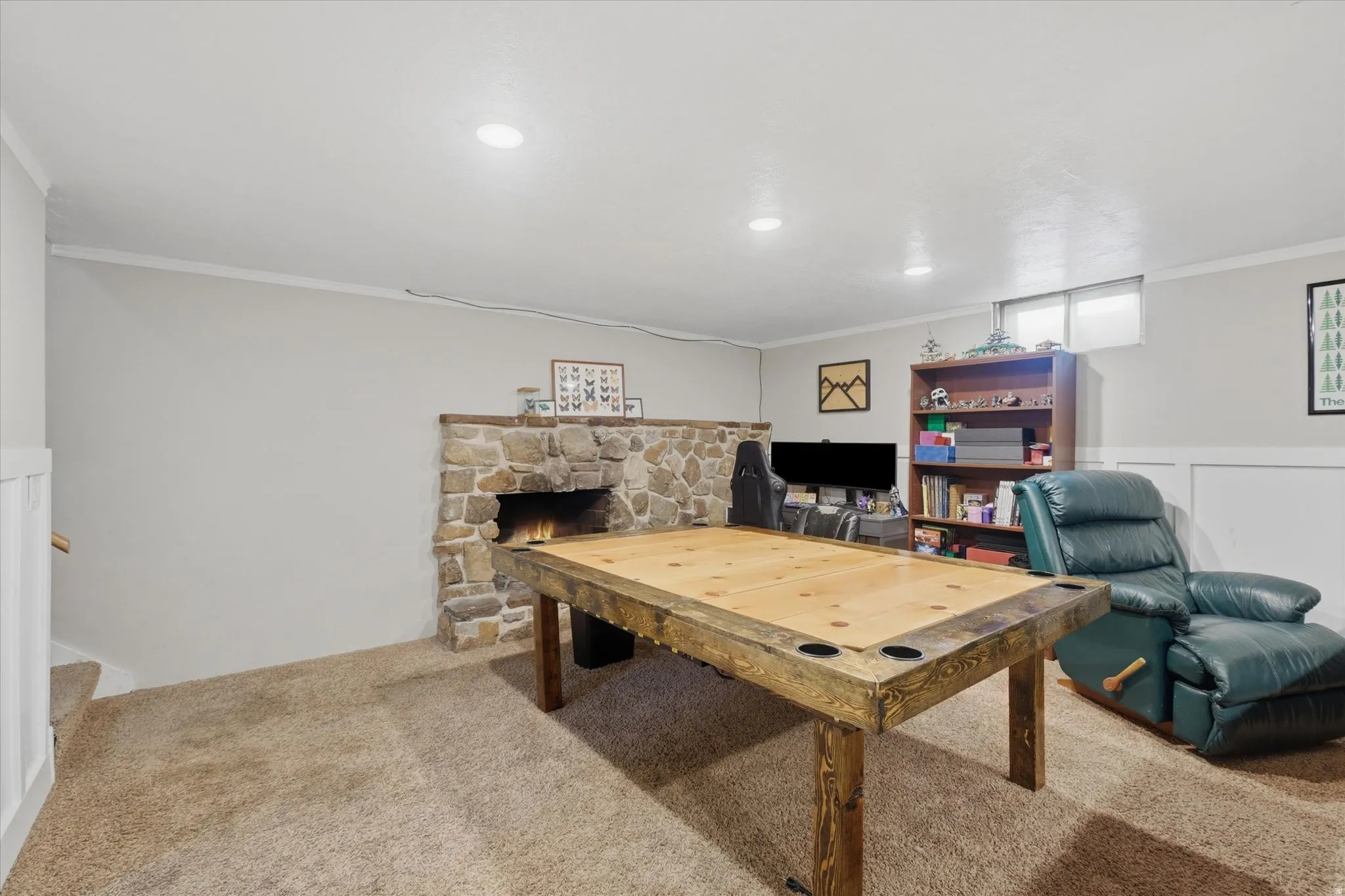 Recreation room featuring a stone fireplace, recessed lighting, and a window for natural light