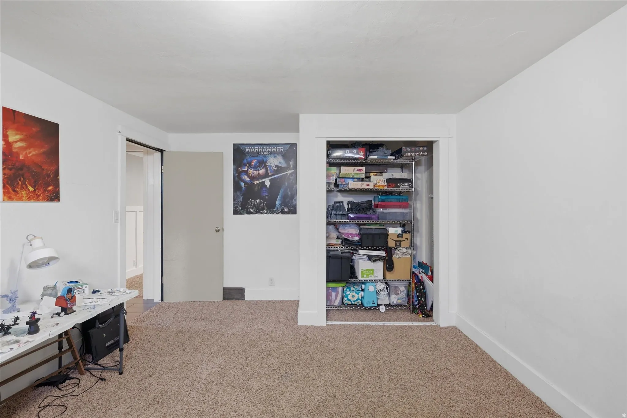 Room featuring light tan carpet flooring, white walls, and a recessed closet with wire shelving