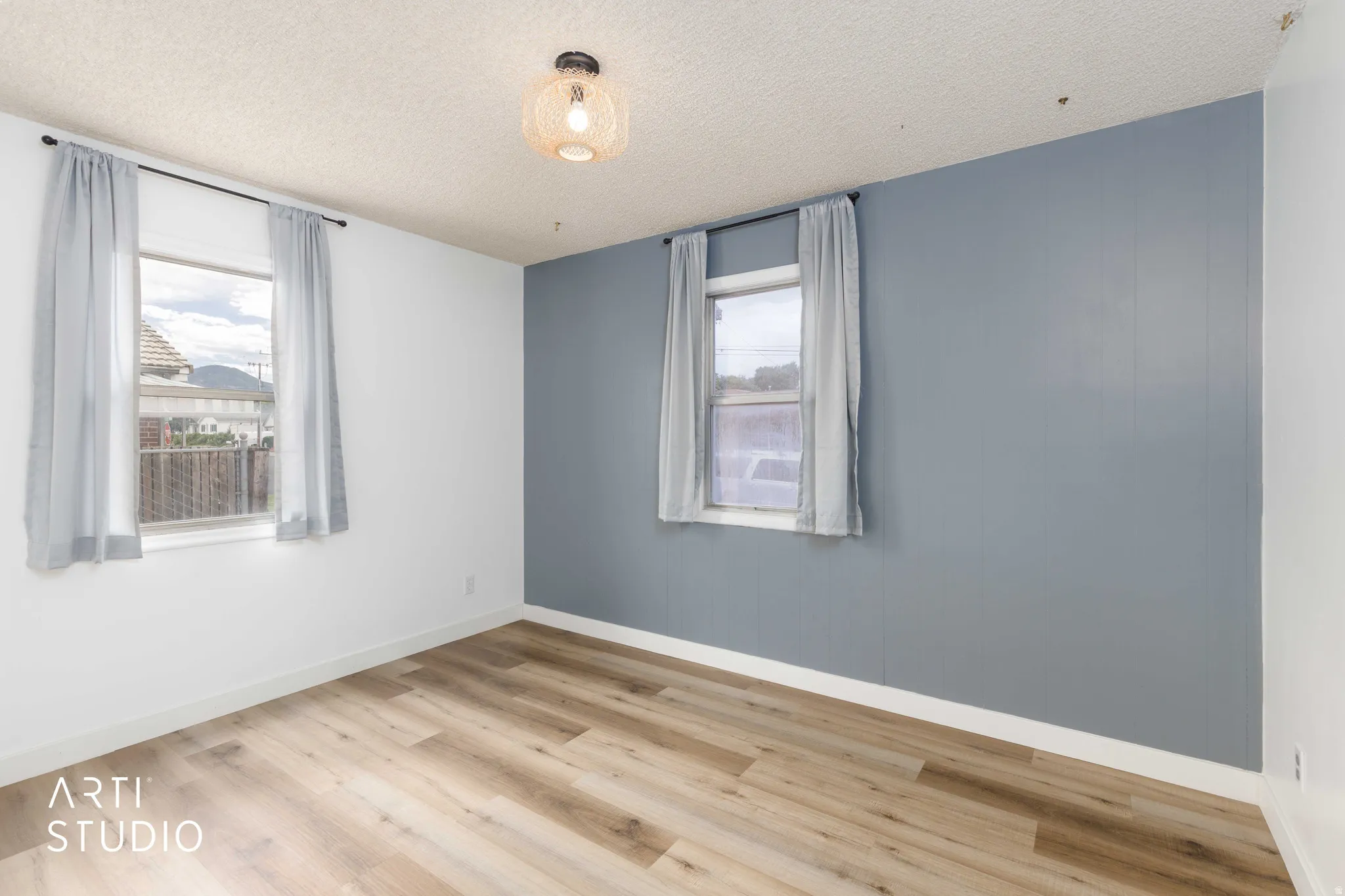 Room featuring wood-finish flooring, white baseboards, and a contemporary ceiling light fixture