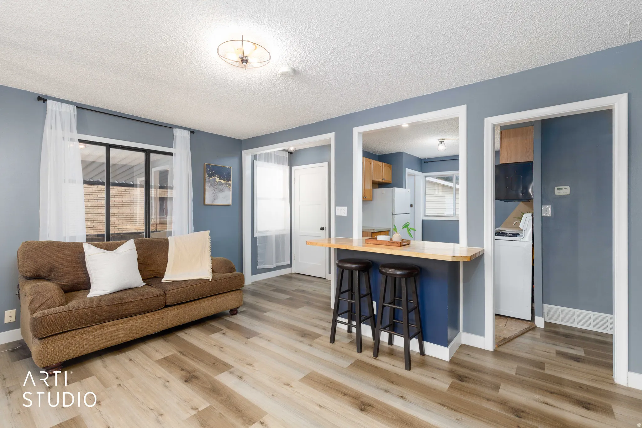 Living area featuring wood-finish flooring, a pass-through counter with a wood-finish surface, and a contemporary ceiling light fixture