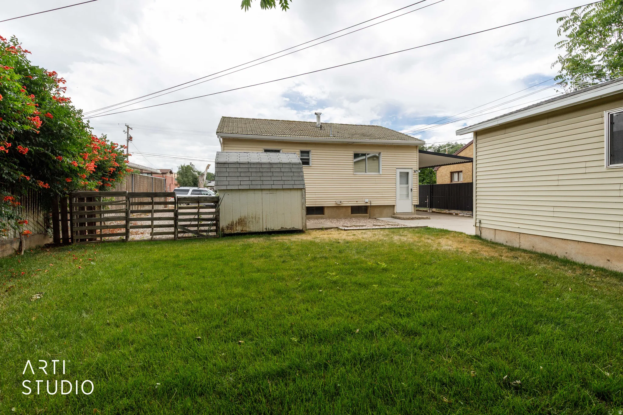 Expansive green lawn with a garden shed and a wooden fence