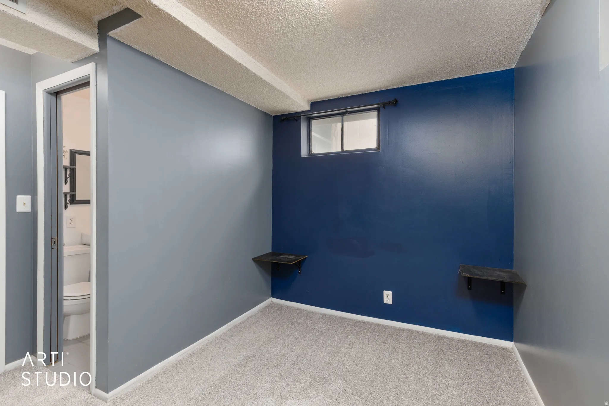 Carpeted room featuring a window, painted walls, and exposed ceiling beams