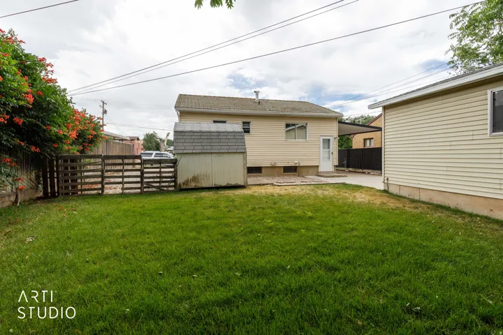 Expansive green lawn with a garden shed and a wooden fence