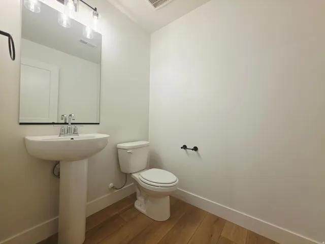 Pedestal sink with chrome faucet, large rectangular mirror, and four-light vanity fixture