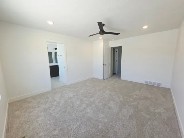 Spacious room featuring light-colored carpeting and white walls