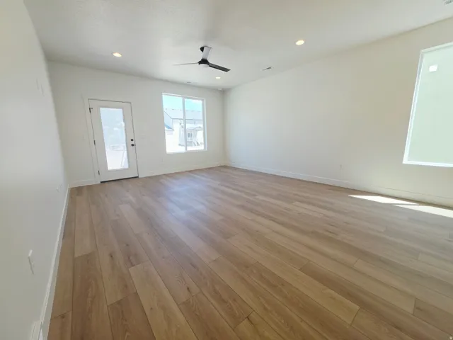 Spacious room featuring light wood-finish flooring, recessed lighting, and a modern ceiling fan