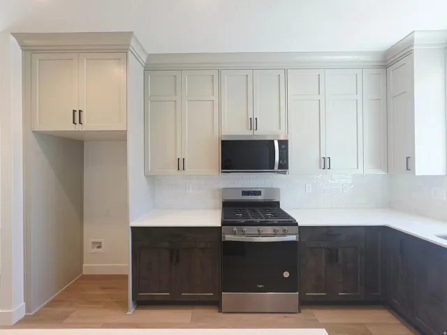 Contemporary kitchen featuring two-tone cabinetry, white countertops, and a subway tile backsplash