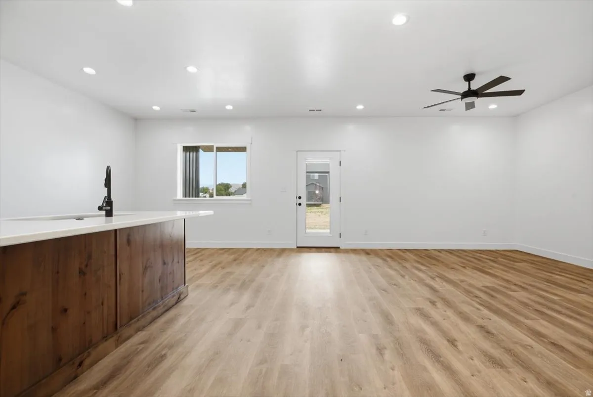 Open-concept living space with wood-finish flooring, recessed lighting, and a contemporary ceiling fan