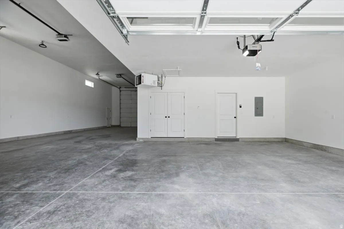 Spacious garage featuring a concrete floor, two white entry doors, and an overhead garage door with opener