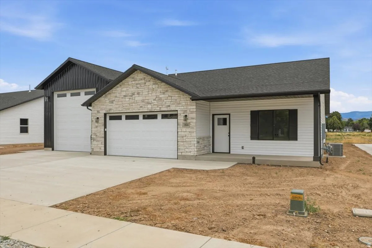 Modern farmhouse exterior featuring light-colored stone accents, white siding, and dark trim