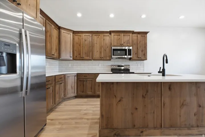Kitchen featuring wood-finish cabinetry, white countertops, and stainless steel appliances