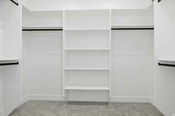 Built-in white shelving system featuring multiple storage compartments and matte black hanging rods