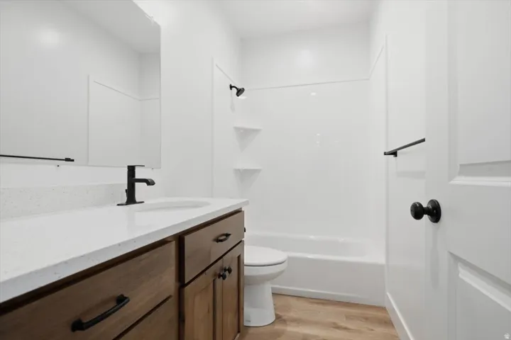 Bathroom featuring a wood-finish vanity with a light-toned countertop, undermount sink, and matte black faucet