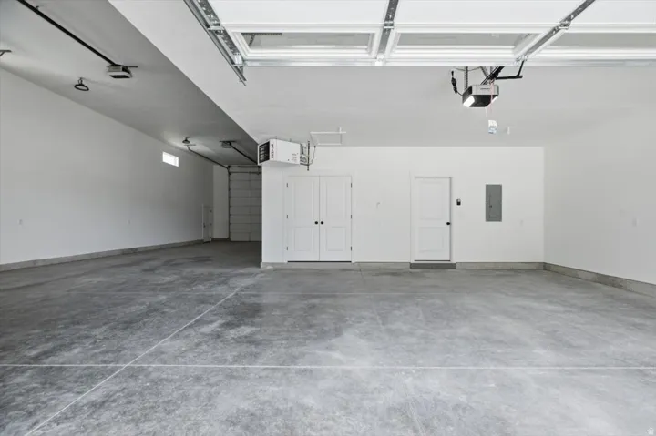 Spacious garage featuring a concrete floor, two white entry doors, and an overhead garage door with opener