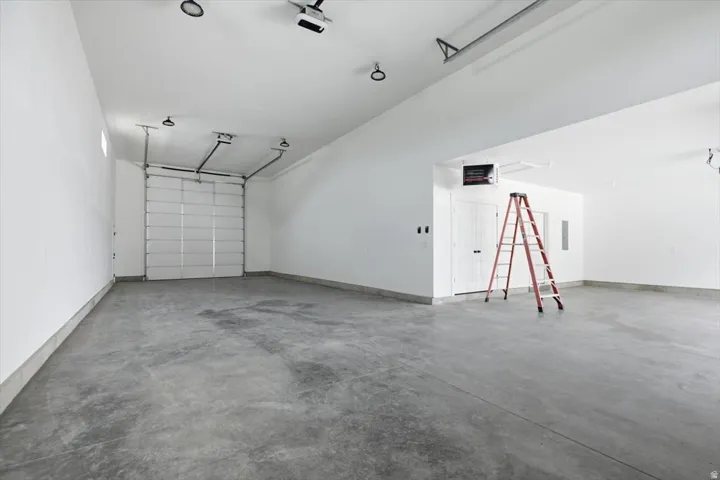 Spacious garage with a concrete floor, bright white walls, and an overhead garage door