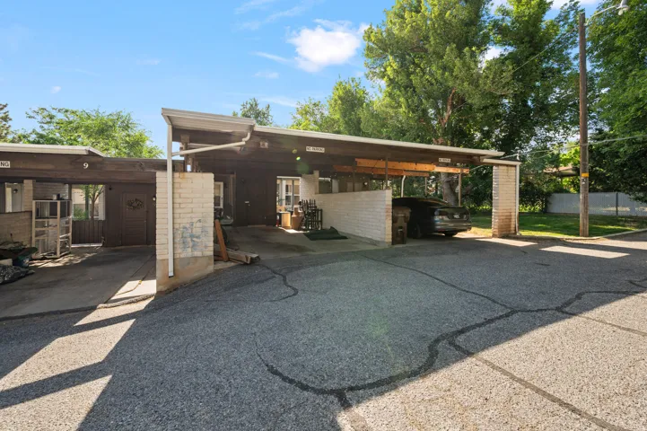 Carport structure with wood-finish beam accents and white brick supports