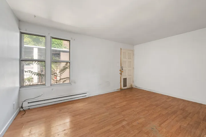 Room featuring wood-finish flooring, white painted walls, and two large window panes