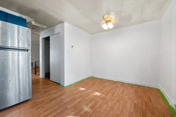 Room featuring wood-finish flooring, white painted walls, and a brass-finished ceiling light fixture