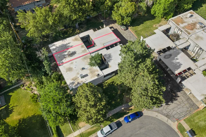 Property featuring a multi-level structure with flat roofs, surrounded by mature trees and green landscaping