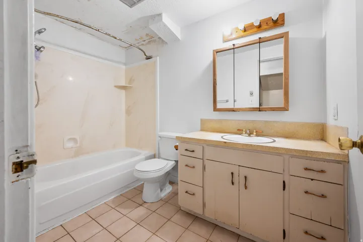 Bathroom featuring a bathtub with a shower kit and a vanity with a drop-in sink