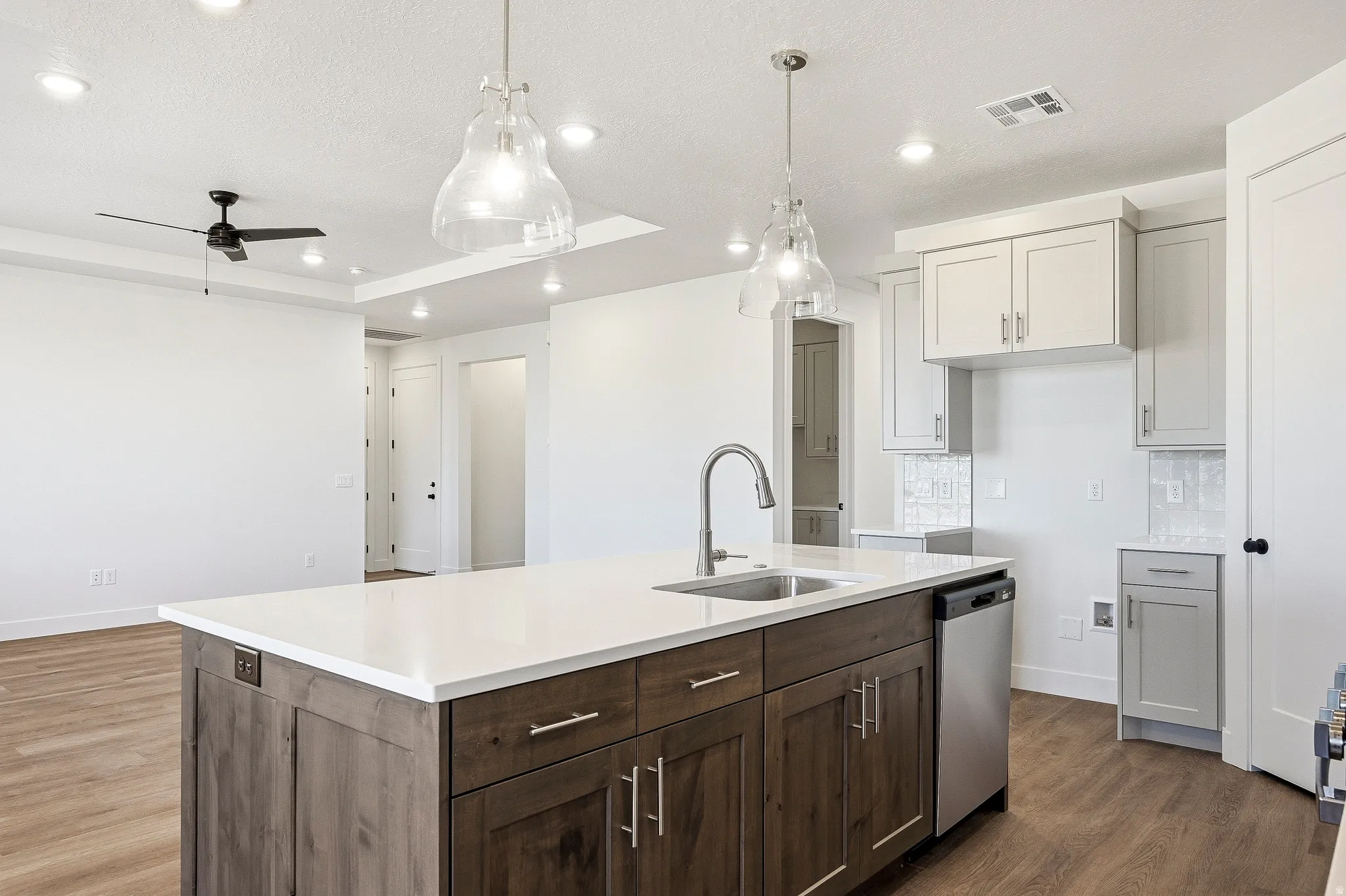 Kitchen island featuring a white countertop, undermount sink, and stainless steel faucet