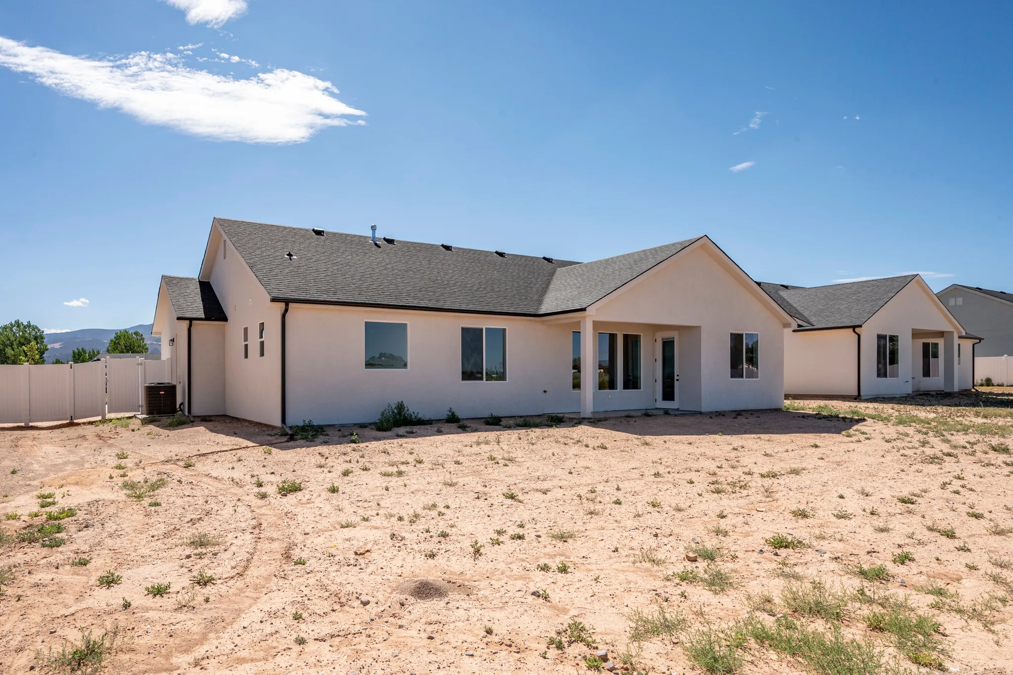 Modern stucco exterior with a dark shingle roof and multiple windows