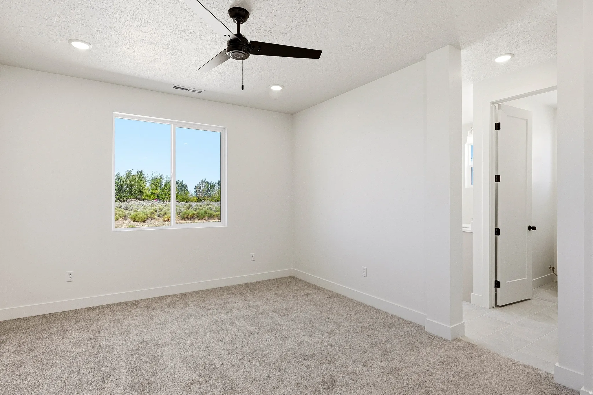 Spacious room featuring a large window, recessed lighting, and a ceiling fan