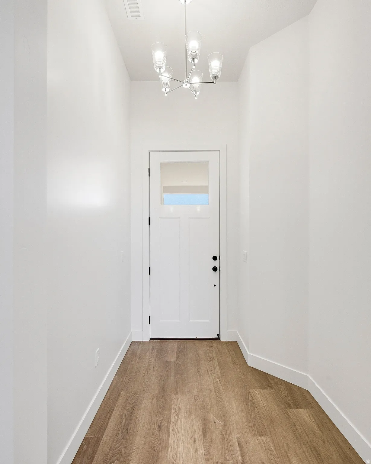 Entryway with wood-finish flooring, white walls, and a contemporary chandelier