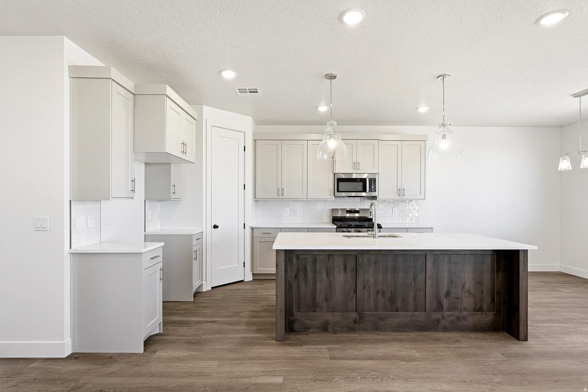 Contemporary kitchen featuring an expansive center island with dark wood-finish paneling and a light-toned countertop