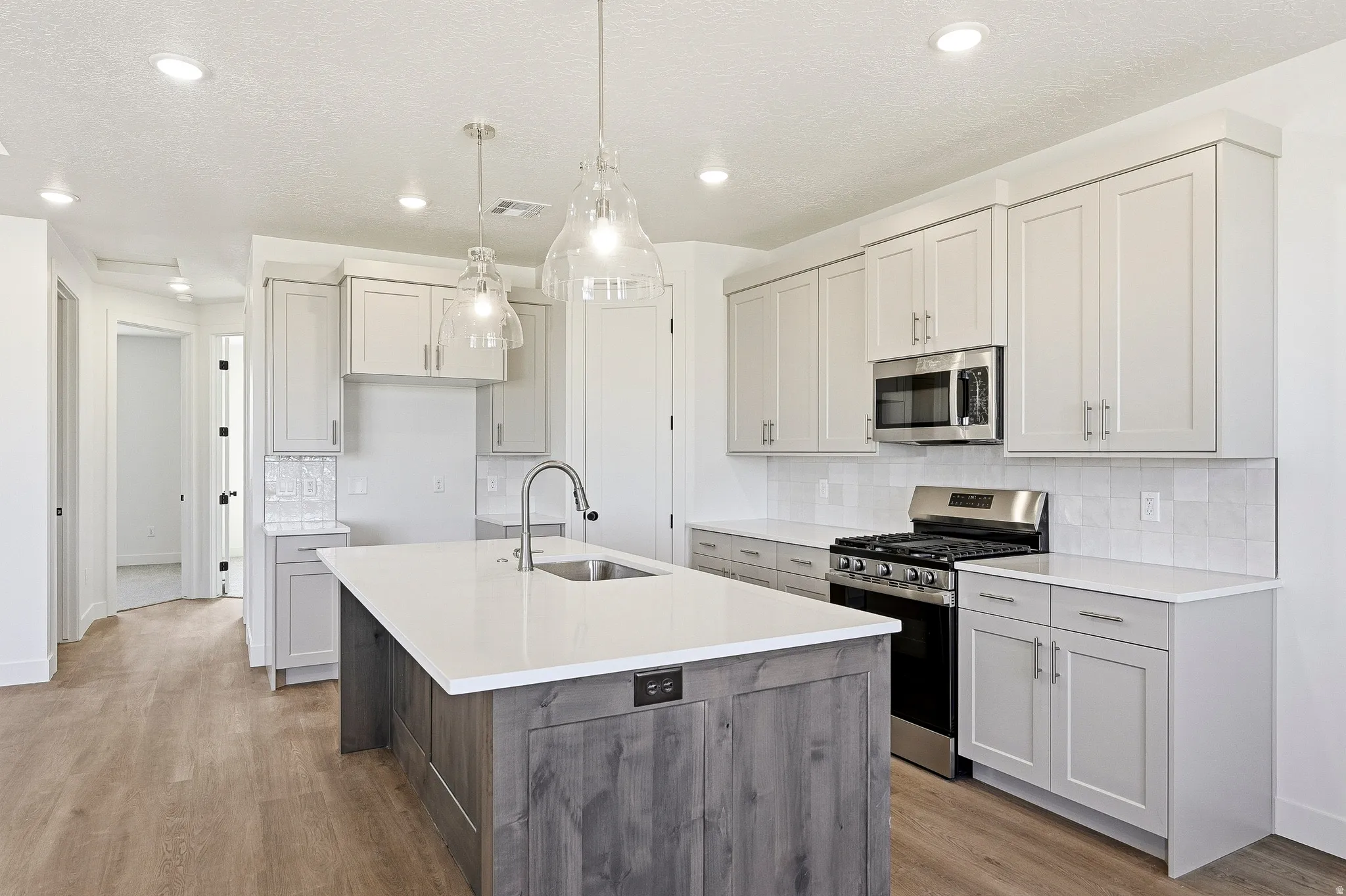 Modern kitchen featuring a central island with a built-in sink and pendant lighting