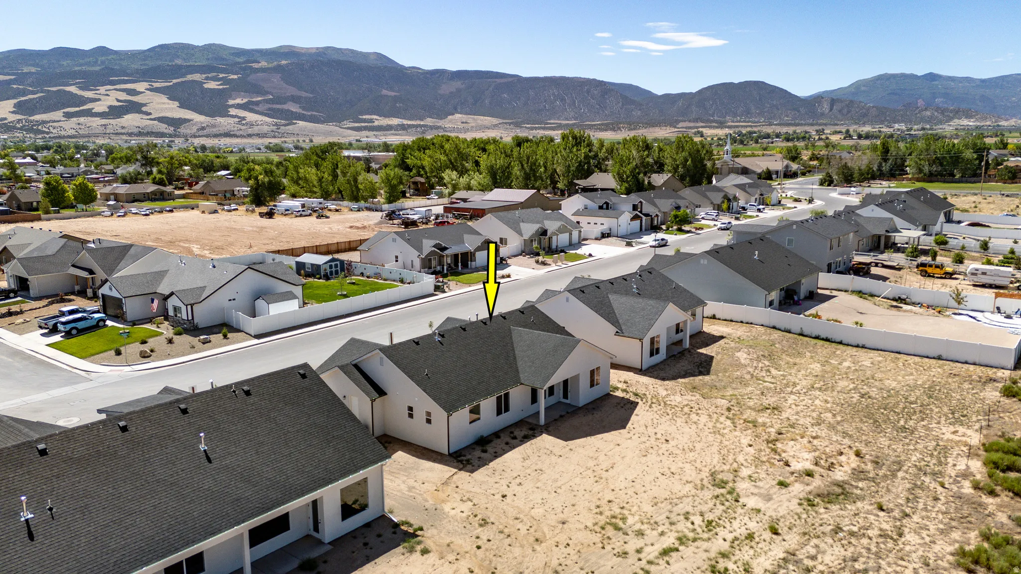 Aerial perspective showcasing a single-story residence with a dark shingled roof and light-colored siding