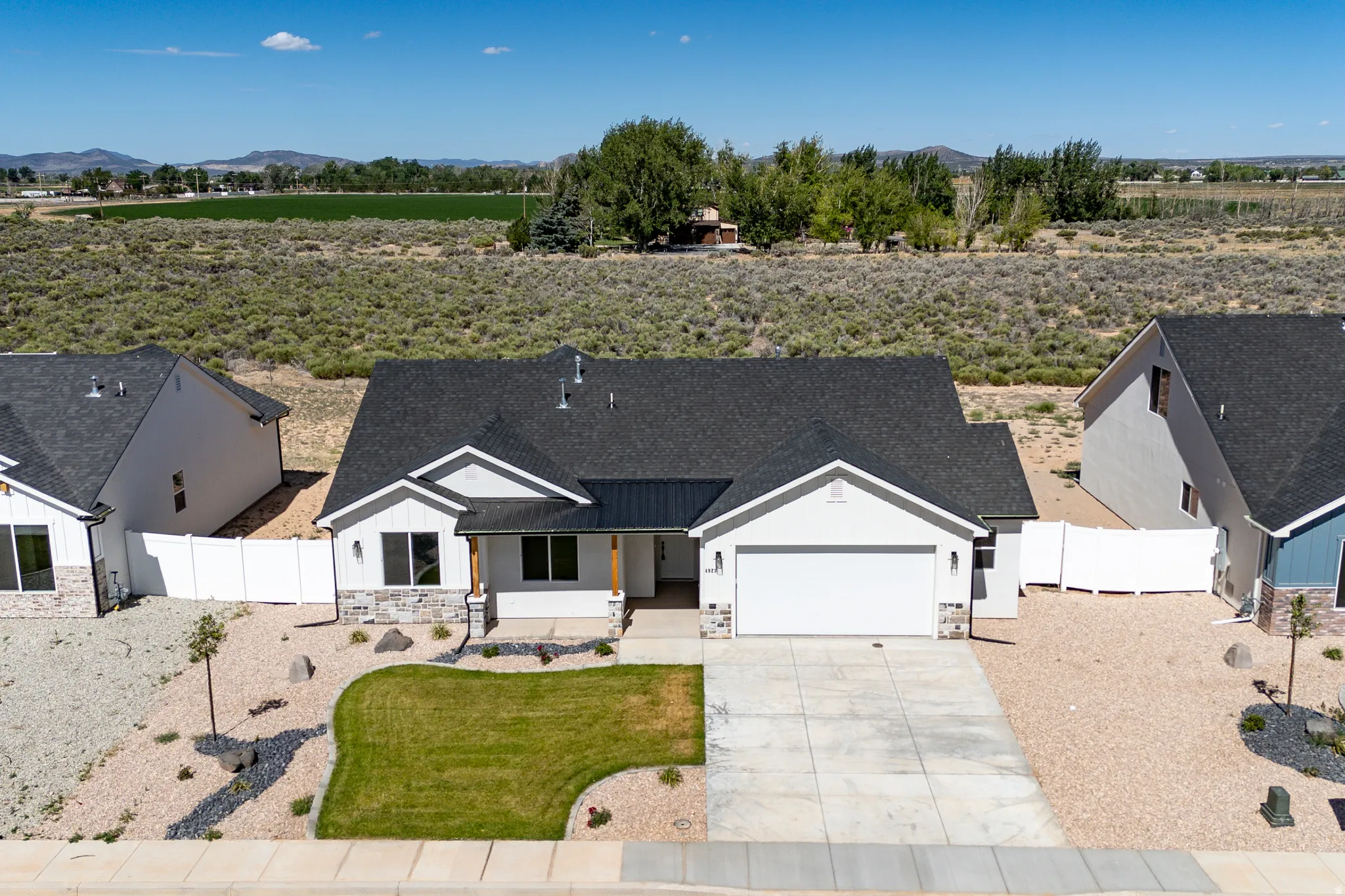 Modern ranch-style home featuring a dark shingle roof and white siding with stone accent detailing