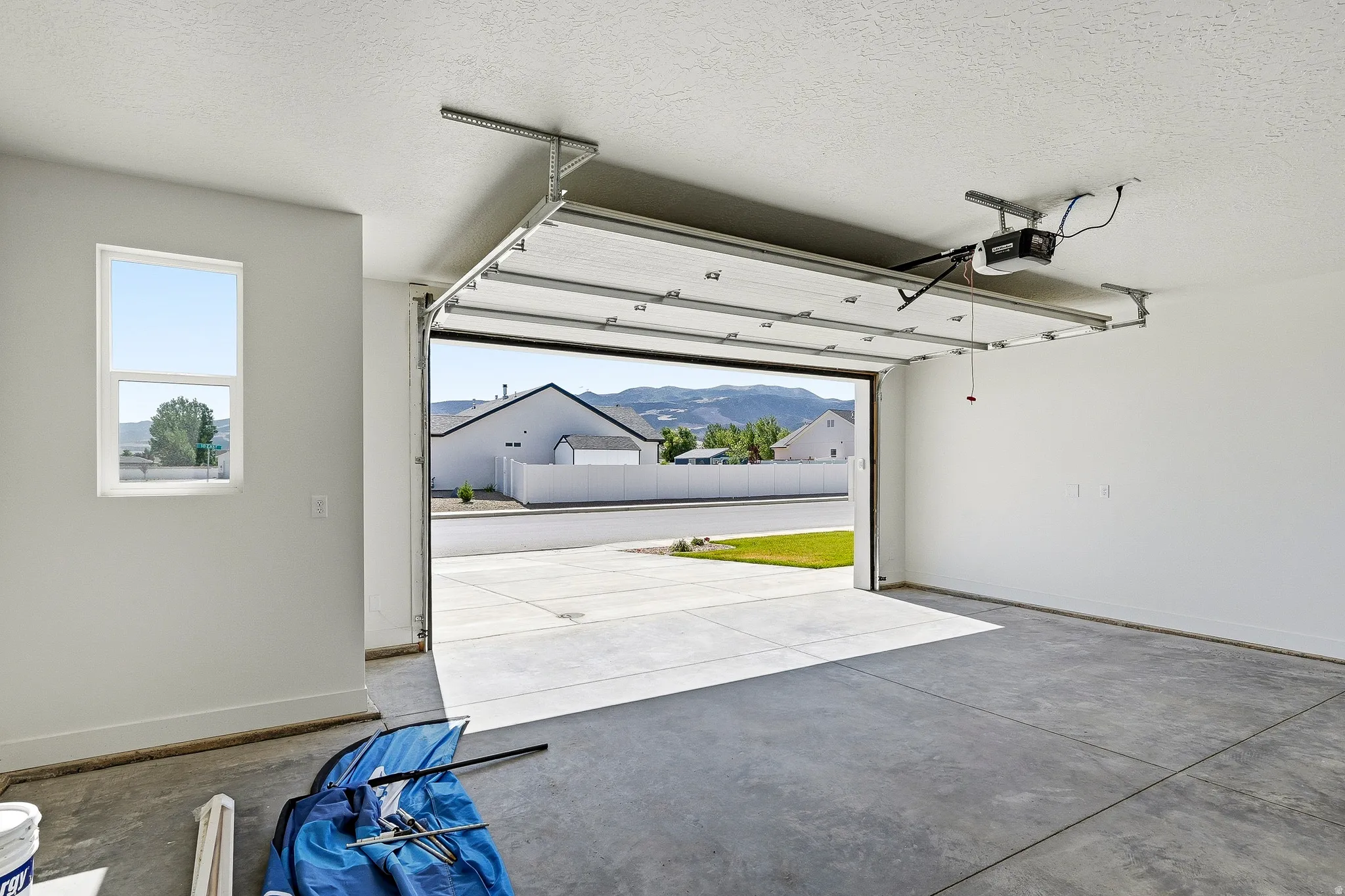 Spacious two-car garage with a concrete floor, automatic garage door opener, and a side window providing natural light
