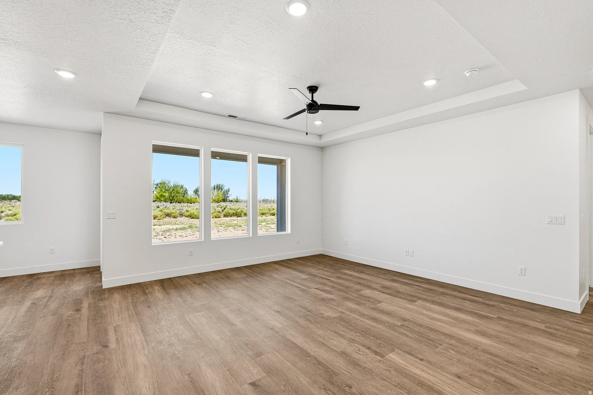 Spacious room featuring wood-finish flooring, recessed lighting, and a ceiling fan