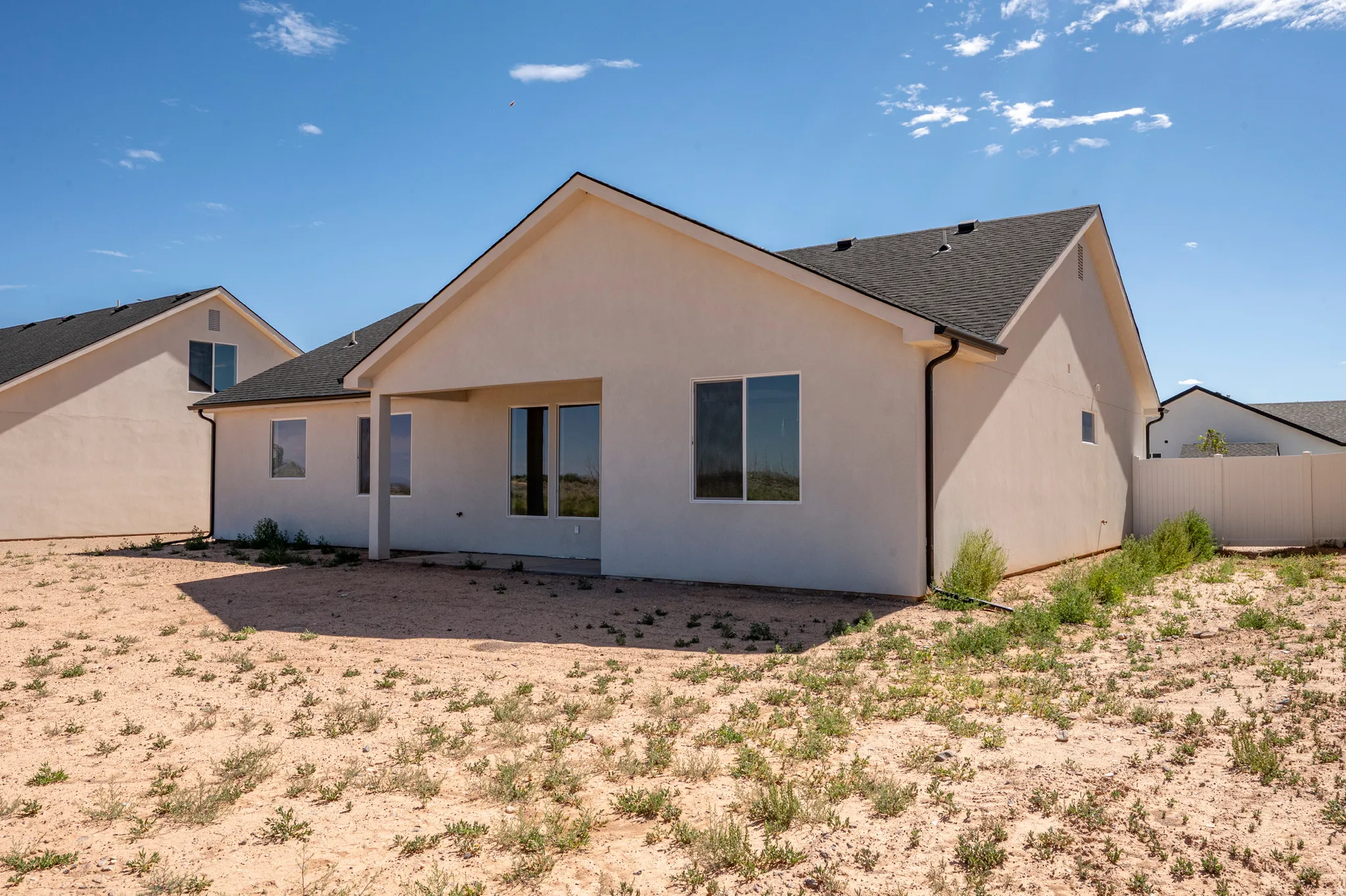 Rear exterior featuring a covered patio, multiple windows, and a partially fenced yard